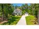 Aerial view of a two-story home with well-manicured lawn and separate garage, surrounded by lush green trees, on a sunny day at 474 Woodspring Rd, Mount Pleasant, SC 29466