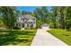 Charming two-story home with a well-manicured lawn and separate garage, surrounded by lush green trees, on a sunny day at 474 Woodspring Rd, Mount Pleasant, SC 29466