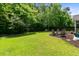 Serene backyard with manicured lawn, mature trees, and a cozy fire pit seating area for relaxation at 5451 Kings River Dr, North Charleston, SC 29420