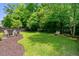 Spacious backyard featuring a well-maintained lawn, a cozy fire pit area, and a wooded perimeter for privacy at 5451 Kings River Dr, North Charleston, SC 29420