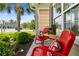 Cozy front porch with red metal chairs, decorative pillows, and a small table surrounded by lush landscaping at 5451 Kings River Dr, North Charleston, SC 29420