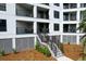 A closer view of the condo building's exterior showing balconies, stairs, and landscaped grounds at 8000 Palmetto Dr # 104-A, Isle of Palms, SC 29451