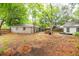 Wide shot of a backyard featuring a brick house, mature trees, and scattered foliage on the ground at 9887 Midview Dr, Ladson, SC 29456