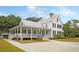 Elegant multi-story home with wrap-around porch, mature trees, and brick driveway at 1011 Old Field Dr, Summerville, SC 29483
