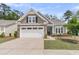 Charming single-story home with a two-car garage, stone accents, manicured lawn, and a welcoming front porch at 1011 Old Field Dr, Summerville, SC 29483