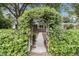 Charming brick home featuring a flower-covered archway, walkway, and manicured green hedges at 1023 Shelley Rd, Charleston, SC 29407