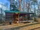 Charming log cabin exterior with green roof, a cozy front porch, and surrounded by mature trees at 107 Bessie Ln, Bonneau, SC 29431