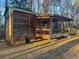 Rustic cabin with green metal roof, inviting front porch with chairs, and woodland surroundings at 107 Bessie Ln, Bonneau, SC 29431