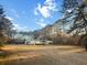 Charming home featuring a large yard, metal carport, and surrounded by beautiful trees under a bright sky at 107 Bessie Ln, Bonneau, SC 29431