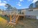 Back view of home features a wooden deck with stairs, gray vinyl siding, and a large yard at 107 Bessie Ln, Bonneau, SC 29431