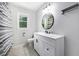 Bright bathroom with white vanity, neutral walls, and a stylish round mirror with a window at 115 Myers Rd, Summerville, SC 29486