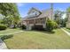 Inviting home with a covered front porch, lush green lawn, and mature trees enhancing its curb appeal at 115 S Ainsdale Dr, Charleston, SC 29414