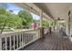 Spacious front porch with wooden flooring, classic white railings, brick supports, and views of the neighborhood at 115 S Ainsdale Dr, Charleston, SC 29414