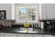 Close up on kitchen sink area, featuring black granite countertops and white cabinetry at 115 S Ainsdale Dr, Charleston, SC 29414