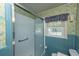 Bathroom featuring a shower with glass doors, blue tile accents, and a window at 1226 Forestwood Dr, Charleston, SC 29407