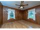 Bedroom with hardwood floors, wood paneling, a ceiling fan, and windows with decorative curtains at 1226 Forestwood Dr, Charleston, SC 29407