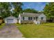 Charming home features a detached garage, green lawn, and inviting front porch at 1226 Forestwood Dr, Charleston, SC 29407