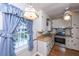 Cozy kitchen features white cabinets, blue curtains, and stainless steel appliances at 1226 Forestwood Dr, Charleston, SC 29407
