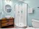 Bright bathroom featuring a glass shower stall, wood vanity, and round mirror at 123 Jungle Rd, Edisto Island, SC 29438