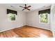 Sunlit bedroom featuring hardwood floors, two windows with leafy views, and a ceiling fan at 1405 S Edgewater Dr, Charleston, SC 29407