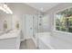 All-white bathroom featuring a glass shower, soaking tub, and a large window with natural light at 1938 Oak Tree Ln, Mount Pleasant, SC 29464