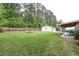 Large backyard with lush green grass, fire pit, wooded boundary, and detached garage at 203 Red Fox Run, Summerville, SC 29485