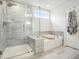 Bathroom featuring a glass-enclosed shower, a soaking tub, and neutral gray tile at 2064 Parish House Cir, Johns Island, SC 29455