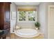 Bathroom featuring a soaking tub, dark wood vanity, tile flooring, and a bright window for natural light at 2206 Weepoolow Trl, Charleston, SC 29407