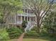 Charming two-story home with double porches, white railings, brick foundation, and lush landscaping at 2206 Weepoolow Trl, Charleston, SC 29407