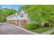 Townhome with cream siding and red brick bottom, surrounded by lush trees and landscaping at 241 Howle Ave # H, Charleston, SC 29412