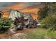 View of the backyard with grass, trees, and a blue-green house set against a colorful sunset at 2729 Battery Pringle Dr, Johns Island, SC 29455