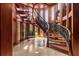 A gorgeous curved wood staircase with a decorative iron railing and abundant natural light from surrounding windows at 2970 Roseville Rd, Wadmalaw Island, SC 29487