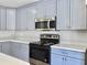 Modern kitchen with stainless steel appliances, light countertops, and stylish gray cabinetry at 341 Sugar Hill Rd, Saint George, SC 29477