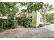 View of light green home with gravel driveway, surrounded by lush foliage at 3.5 Kracke St # C, Charleston, SC 29403