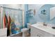 Themed bathroom with surf board shower curtain, white single sink vanity and round mirror at 477 Spanish Wells Rd, Summerville, SC 29486