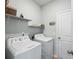 Laundry room with a white washer and dryer, shelves, ironing board, and a door leading out at 477 Spanish Wells Rd, Summerville, SC 29486