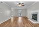 Open living room with fireplace, wood-look floors, ceiling fan, and a sunlit window at 543 Castle Hall Rd, Mount Pleasant, SC 29464