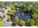 Aerial view of a community featuring a pond, clubhouse, and homes nestled among lush greenery and mature trees at 5514 Colonial Chatsworth Cir, North Charleston, SC 29418