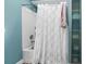Well-lit bathroom featuring a shower/tub combo with a white ruffled curtain and storage shelves at 60 Rice Ln, Edisto Beach, SC 29438
