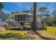 Beautiful exterior view of raised house featuring a screened porch and lush landscaping at 60 Rice Ln, Edisto Beach, SC 29438