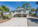 Exterior view of a raised home with palm trees, ample parking, and a well-maintained lawn at 60 Rice Ln, Edisto Beach, SC 29438