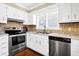 Modern kitchen with stainless steel appliances, white cabinetry, and stylish backsplash at 60 Rice Ln, Edisto Beach, SC 29438