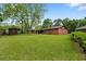 Expansive backyard view showcasing lush lawn, a brick home exterior, and a storage shed on the property at 6305 Brandt St, North Charleston, SC 29406