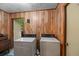 Laundry room with wood paneling, a pair of white washer and dryer units, and a doorway at 6305 Brandt St, North Charleston, SC 29406