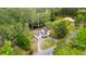 Picturesque aerial view of charming white farmhouse, detached garage, and tranquil pond surrounded by lush greenery at 6373 Farm House Rd, Ravenel, SC 29470