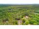 Aerial view showcases a wooded lot with a charming white home and pond at 6373 Farm House Rd, Ravenel, SC 29470