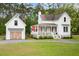 Charming two-story white home with a detached garage and a welcoming front porch at 6373 Farm House Rd, Ravenel, SC 29470