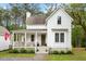 Charming two-story white home with a welcoming front porch and lush landscaping at 6373 Farm House Rd, Ravenel, SC 29470