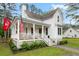 Inviting white home with a classic porch, string lights, and neat landscaping at 6373 Farm House Rd, Ravenel, SC 29470