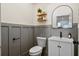 Stylish powder room with gray wainscoting, an arched mirror, and floating shelves at 6373 Farm House Rd, Ravenel, SC 29470